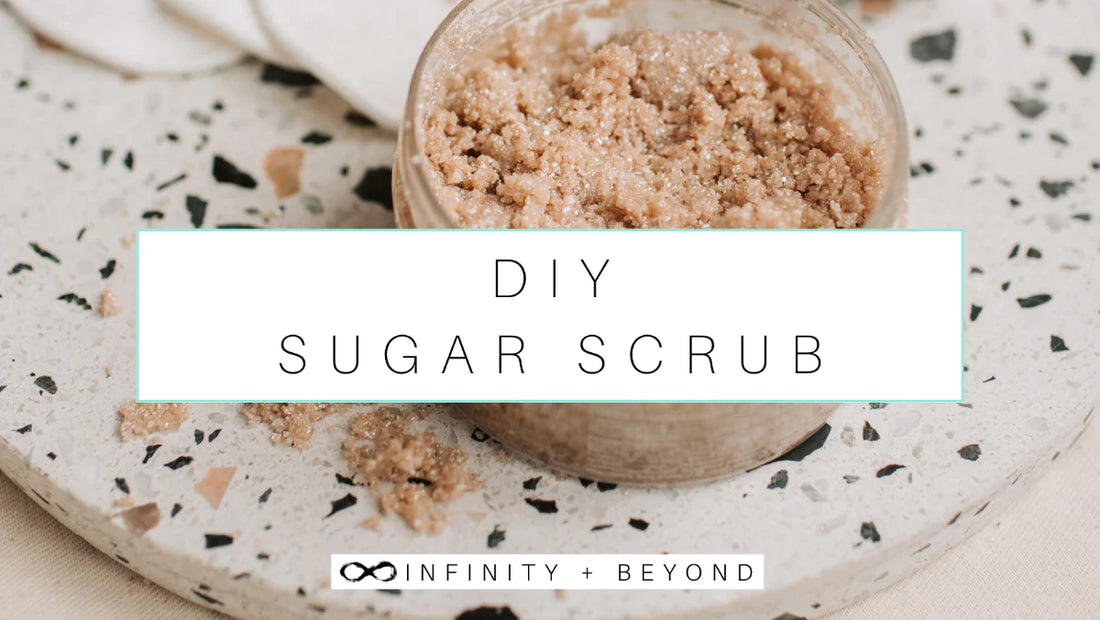 DIY Sugar Scrub. Picture of brown sugar scrub on a speckled clay circular riser with organic cotton face pads in the background.
